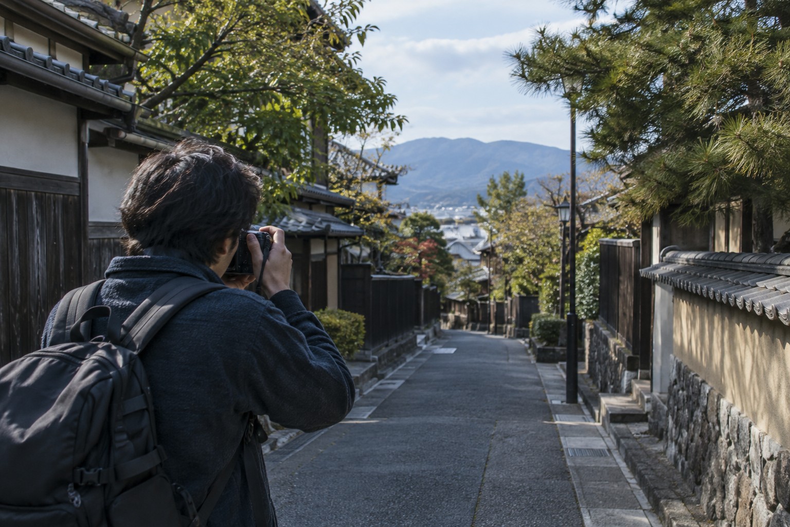 街角でカメラを構えて撮影位置を考える人(AI生成のイメージ)